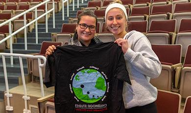 两个学生拿着一件印有地球仪的童年研究t恤.