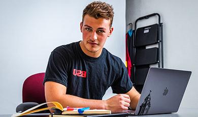 Ryan Kuczer sits at a desk working on a laptop